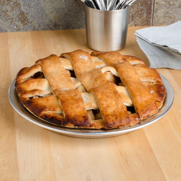 A close-up of a Vollrath aluminum pie pan with a pie on a table.