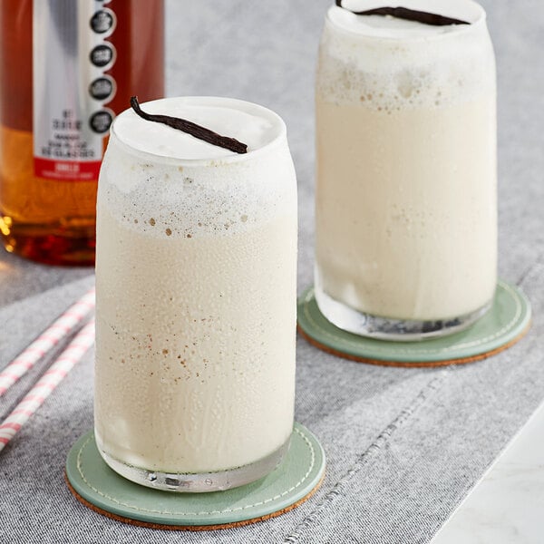 Two glasses of SHOTT vanilla milkshake on coasters with straws.