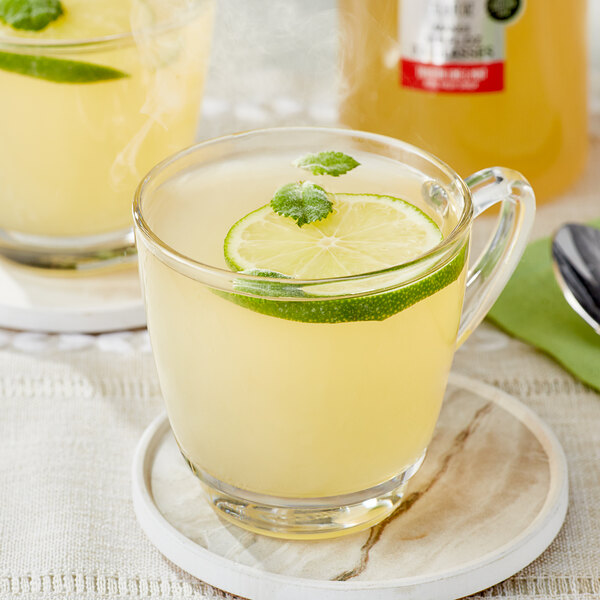 A glass mug of lemonade with a lime and mint garnish.
