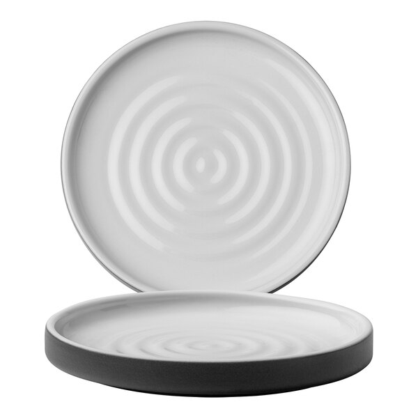 A white stoneware plate with a black circular pattern on the rim.