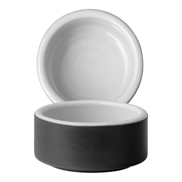 A close-up of a white Chef & Sommelier stackable ramekin with a black lid.