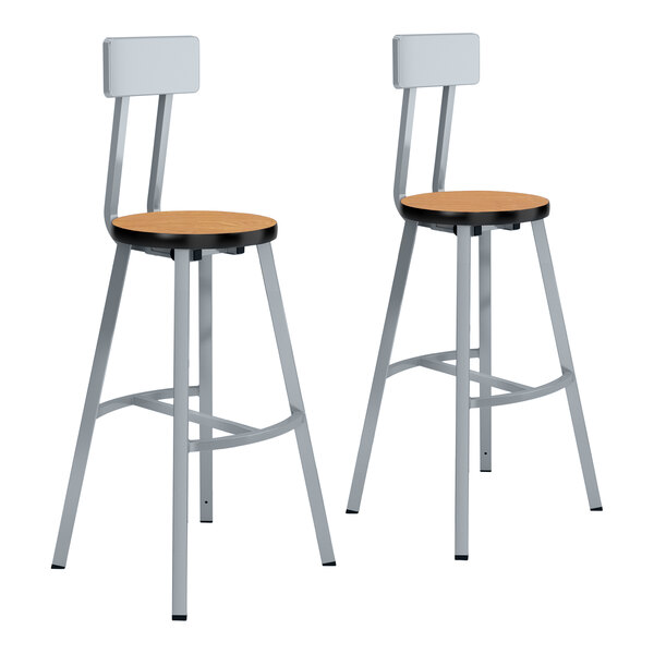 A pair of National Public Seating lab stools with Bannister Oak seats and gray steel legs.