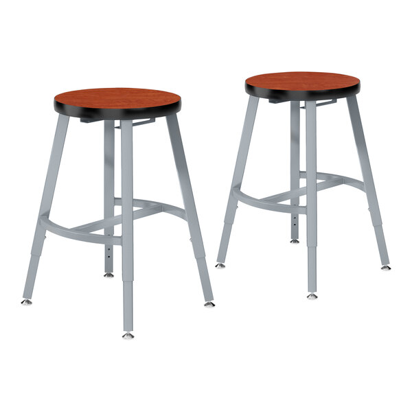 A pair of metal National Public Seating lab stools with Wild Cherry high-pressure laminate seats.