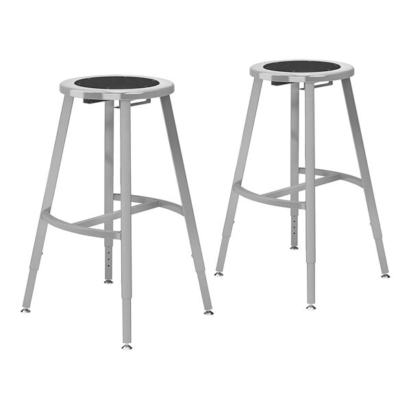 A pair of National Public Seating steel lab stools with black seats.