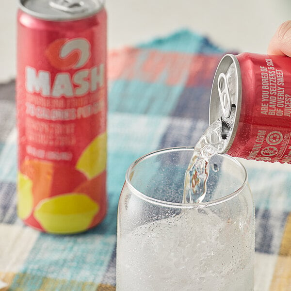A hand pouring Boylan Mash Grapefruit Citrus Zing soda from a red can into a glass of ice.