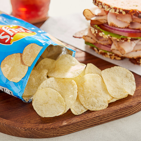 A table in a deli with a sandwich and a bag of Lay's Salt & Vinegar Potato Chips.