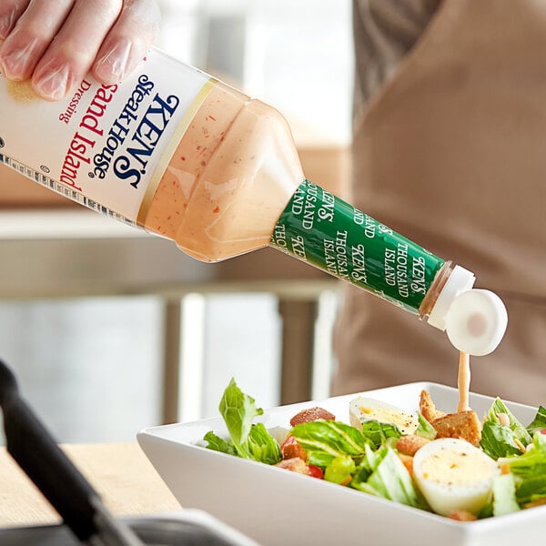 A person pouring Ken's Foods Supreme Thousand Island Dressing onto a salad.