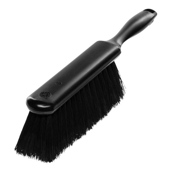 A close up of a Carlisle black counter brush with a handle.
