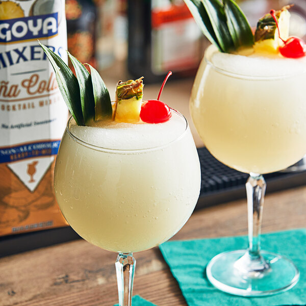 Two glasses of Goya Pina Colada with cherries and pineapples on top.