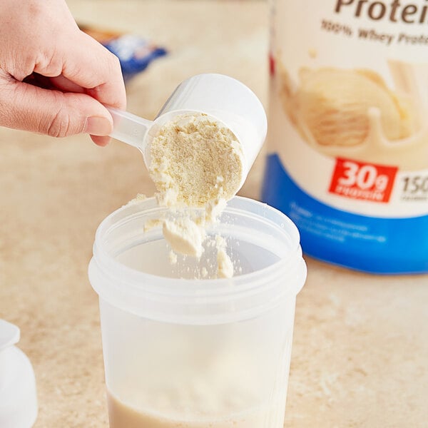 A hand pouring Premier Protein Vanilla Milkshake protein powder into a container.