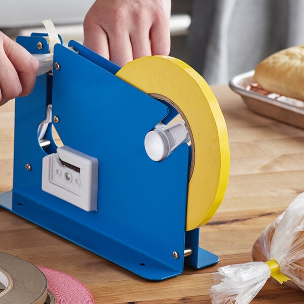 A hand using a yellow and blue Lavex tape dispenser to seal a blue box.