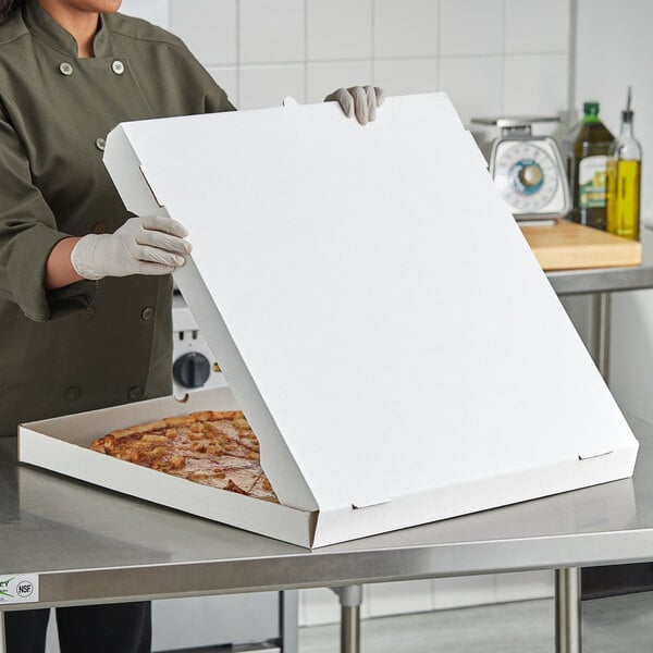 A woman in a chef's uniform holding a white Choice pizza box.