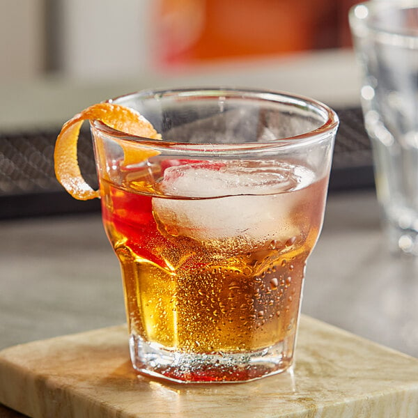An Acopa Memphis old fashioned glass with a drink and ice.
