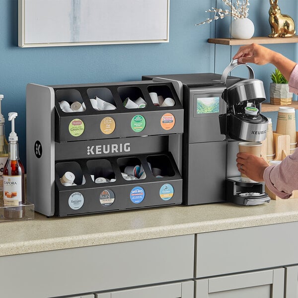 A woman using a Keurig K-3500 coffee maker with a black and white dispenser.