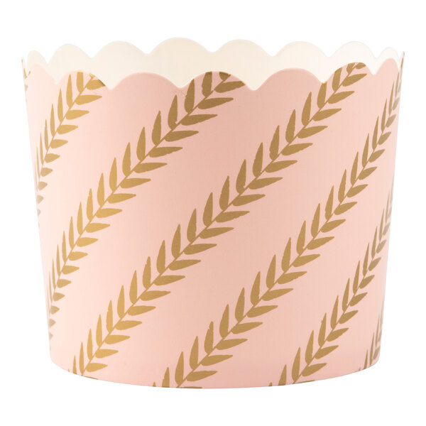 A pink paper baking cup with gold leaves on it.