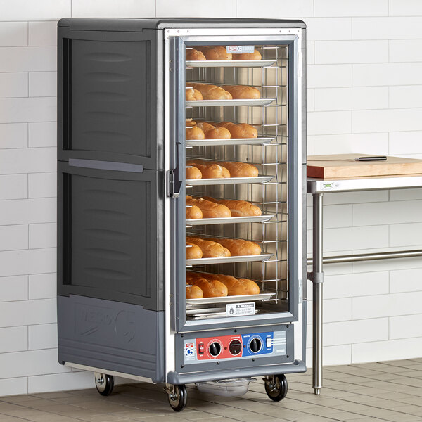 A Metro C5 holding and proofing cabinet with a large clear door holding trays of bread.