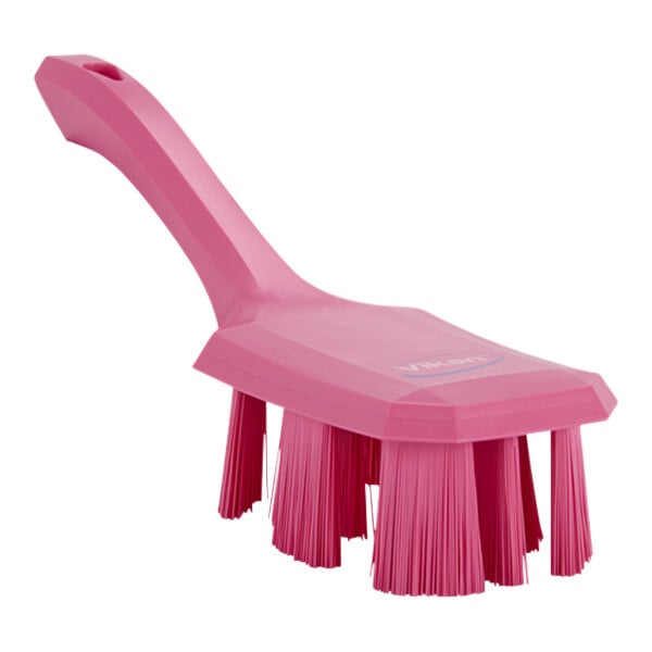 A close-up of a Vikan pink hand brush with short handle and stiff bristles.