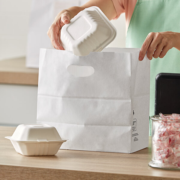 A woman putting food into a white Duro paper bag.