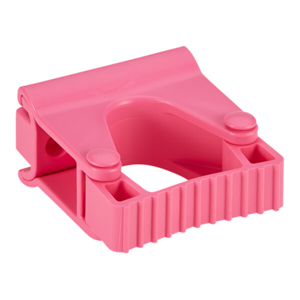 A close up of a pink plastic Vikan wall bracket with holes.