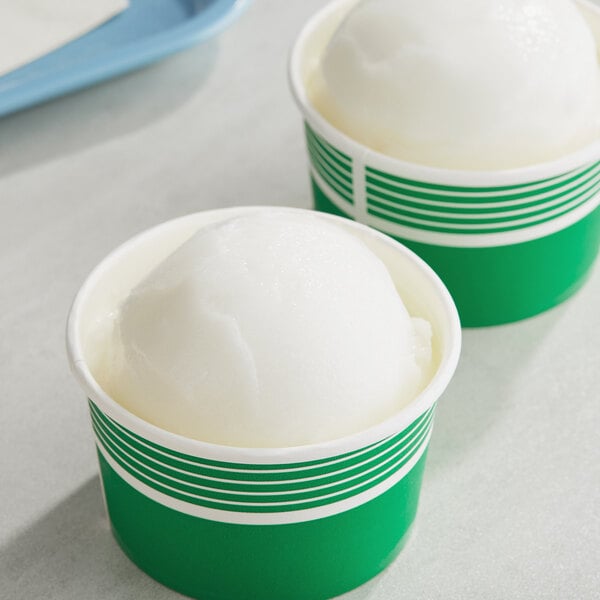 Two green cups of lemon Italian ice with a white ball in each.
