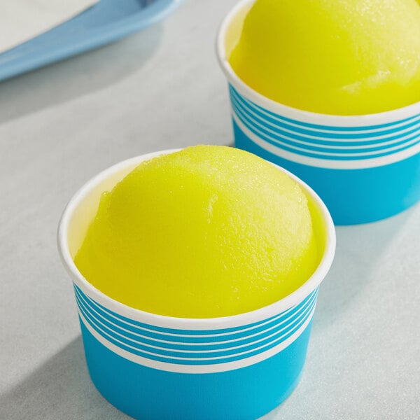 Two cups of yellow and blue Philadelphia Water Ice on a table.