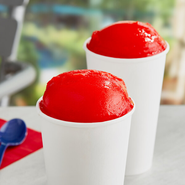 Two cups of Philadelphia Water Ice Cherry Italian Ice with blue spoons.