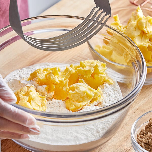 A gloved hand mixes yellow Stratas Golden Sweetex shortening into dough in a bowl.
