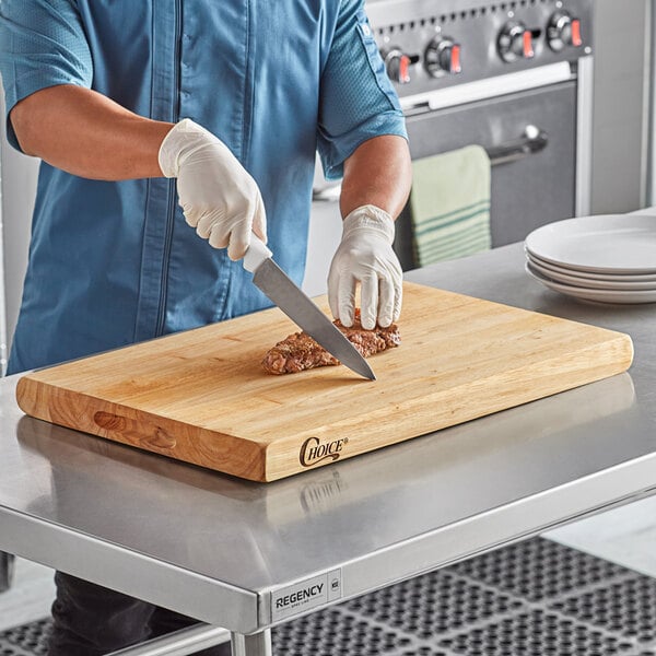 A man cutting meat on a Choice wood cutting board.