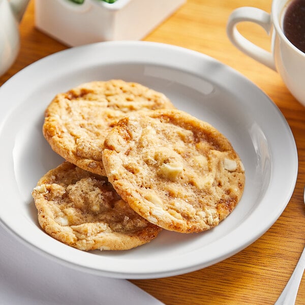 A plate of Sweet Street Desserts salted caramel cookies on a table with a cup of coffee.