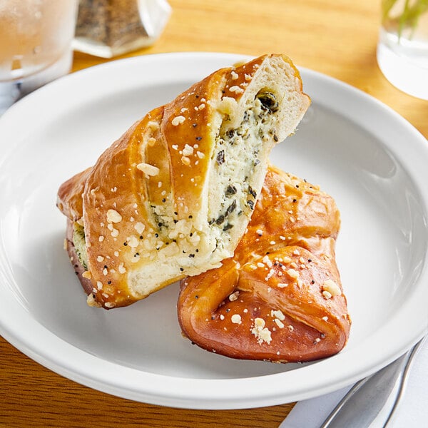A white plate with a Sweet Street spinach and feta stuffed pretzel on it.