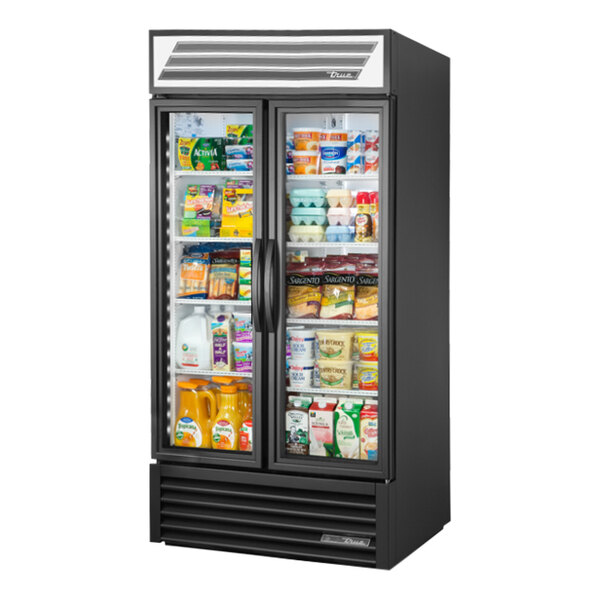 A True refrigerated glass door merchandiser with a glass door full of dairy products.