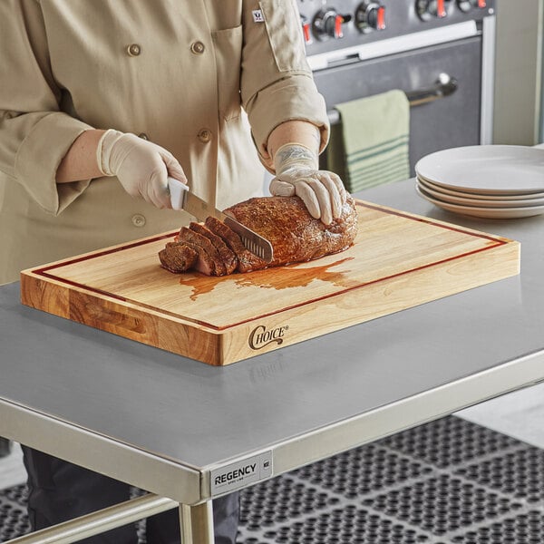 A person cutting meat on a Choice wood cutting board.