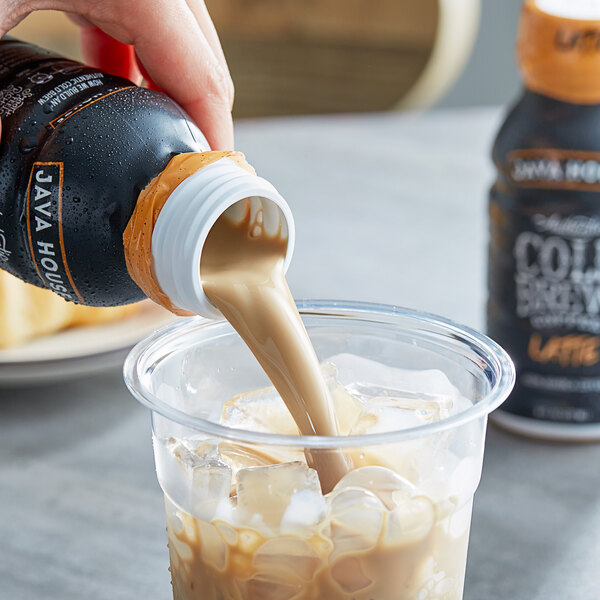 A person pouring Java House Cold Brew Latte into a cup.