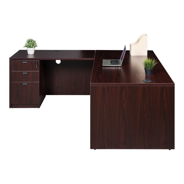 A Boss mahogany laminate desk with a laptop and potted plant on it.
