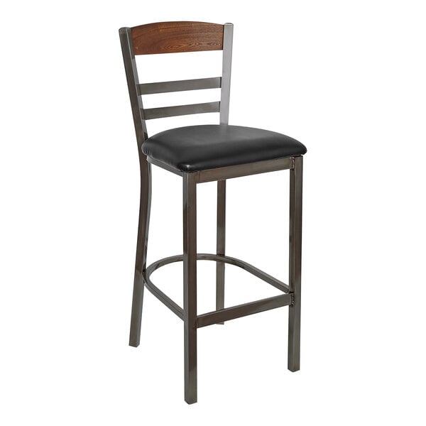 A BFM Seating black steel barstool with wood back and black vinyl seat.