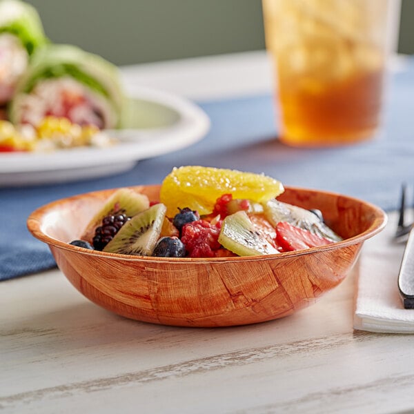 A bowl of fruit salad in a Choice woven wood bowl on a table.