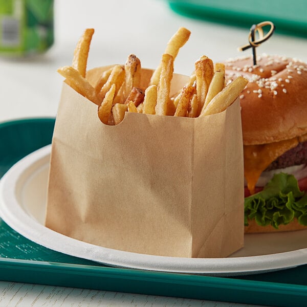 A Bagcraft natural paper bag with a cheeseburger and fries on a plate.