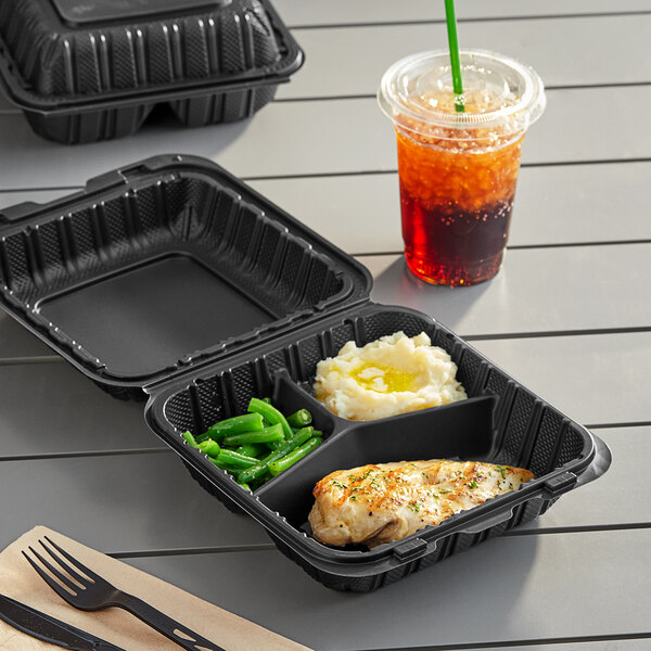 A black Choice 3-compartment take-out container with food and a drink on a tray.