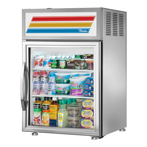 A True countertop glass door refrigerator with various food items inside.