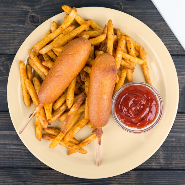 A plate of hot dogs and french fries with a bowl of ketchup on a table.