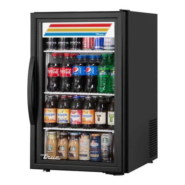 A black True countertop glass door refrigerator full of drinks.