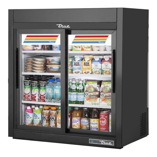 A True dual-glass door countertop refrigerated merchandiser with LED lighting filled with drinks and beverages.