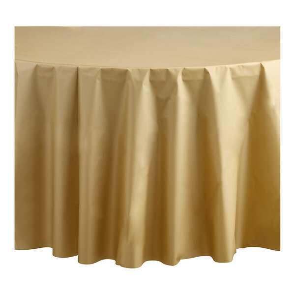 A round table with a metallic gold plastic table cover on top.