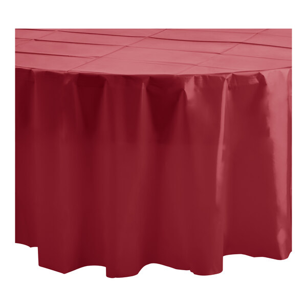 A burgundy Table Mate round plastic tablecloth on a table.
