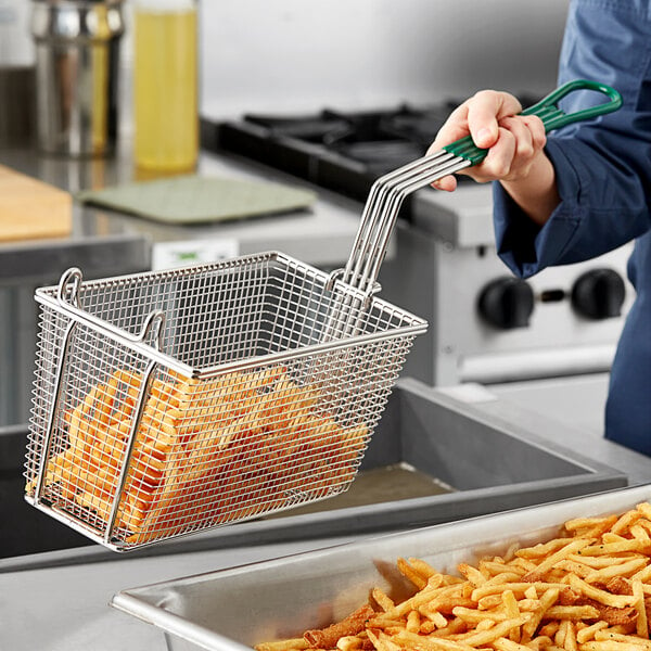 A person holding an Avantco fryer basket full of french fries.