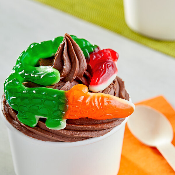 A cup of chocolate ice cream with a Vidal gummy crocodile on top.