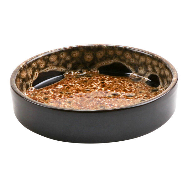 A brown and black cheforward terracotta casserole dish with orange and brown spots.