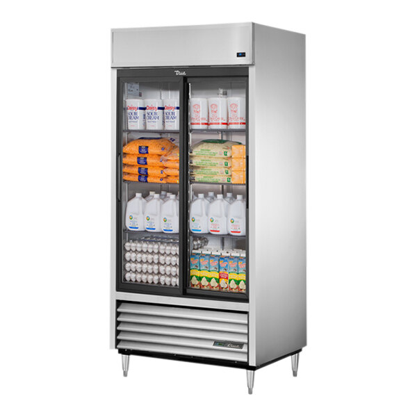 A True 2 section sliding glass door refrigerator full of dairy products and eggs.
