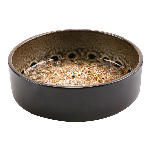 A terracotta bowl with brown spots filled with brown liquid.
