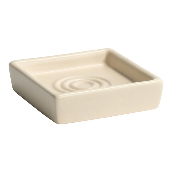 A white square stone soap dish with a ripple pattern in the middle.
